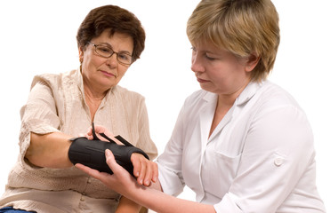 female doctor examining wrist of senior patient.
