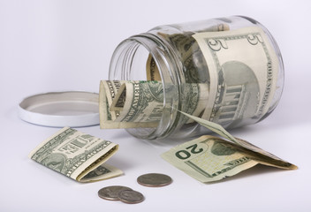 an open glass jar with money, banknotes and coins