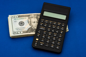 Black calculator with stack of twenty dollar bills