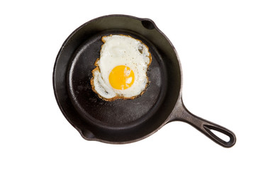 A fried egg in a black iron skillet on a white background, food