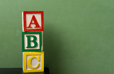 ABC blocks in front of a green chalkboard with copy space