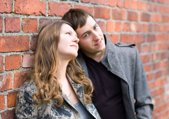Fototapeta na wymiar Romantic couple standing by old brick wall. Focus on girl.
