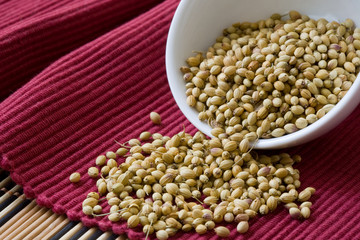 yellow coriander seed on white bowl and red background