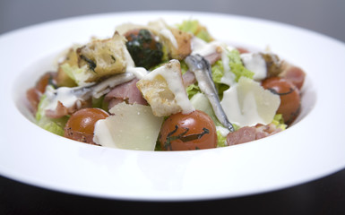 A white bowl of Caesar salad with dressing.
