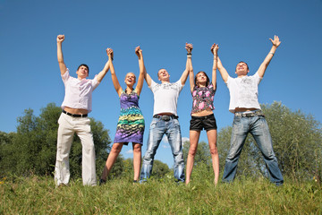 Group of friends with rised hands outdoor in summer