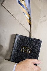 A business man or preacher holidng a copy of the Holy BIble