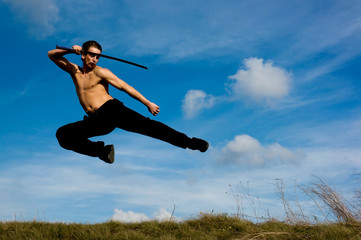 Young handsome man with samurai sword jumping