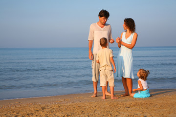 Parents with children standing  at edge of  sea
