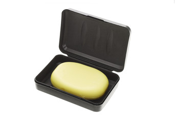 Bar of yellow soap in black container on white background