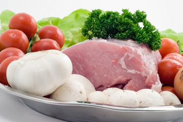 Raw pork on the plate with tomatoes,garlic and mushrooms