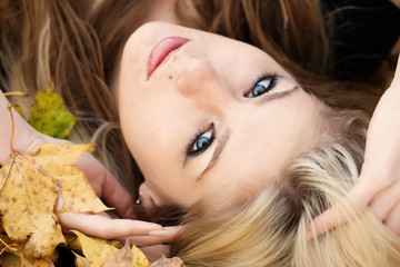 Portrait of young woman lying on autumnal leaves