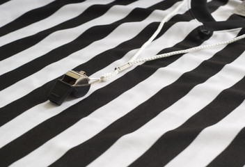 A referee striped shirt with a whistle, sports equipment,