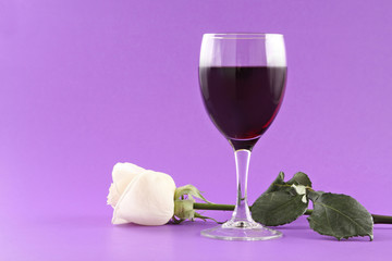glass of red wine and white rose