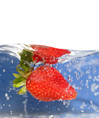 A juicy red strawberry plunging into some water. Shallow DOF.