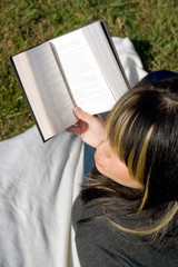 A young woman with highlighted hair reading a book.