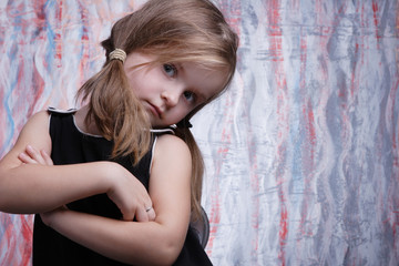 Cute small girl posing in black dress in studio.