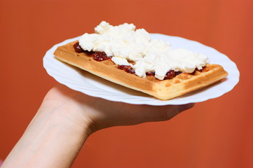 waffle with cream and  strawberry / plum jam on plate in hand