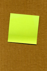 Blank postit note stuck to a cardboard box.