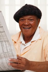 Obraz premium African woman reading a newspaper and smiling