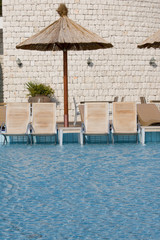 Wooden sunbeds in swimming pool