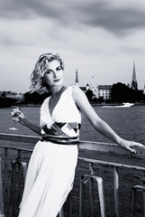 Beautiful blond girl drinks champagne near the river