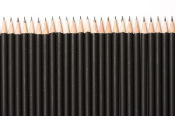 Black pencils lined up on white background.