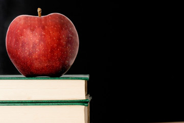 A red apple red on a green book on a black background