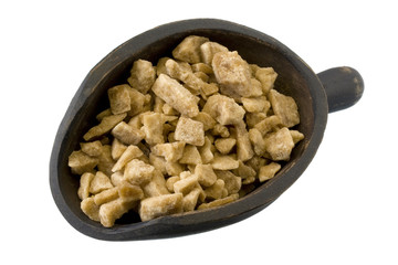 chunks of maple sugar on a wood scoop, isolated on white