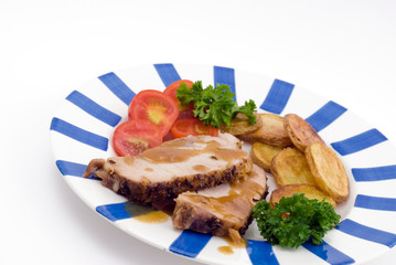 Roasted pork with potatoes, tomatoes and fresh green parsley