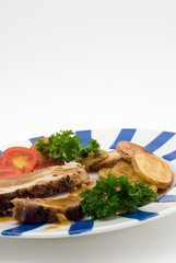 Roasted pork with potatoes, tomatoes and fresh green parsley