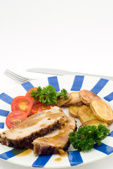 Roasted pork with potatoes, tomatoes and fresh green parsley