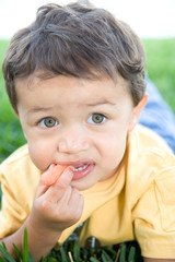 Adorable little boy snacking on a carrot