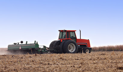 Obraz premium Farm tractor discing a field after harvest