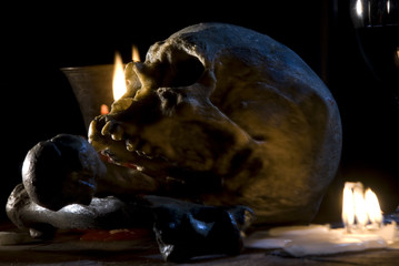 real skull and bones over a table, with candles and chalice.