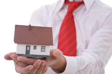 real estate concept with a businessman holding a mini house