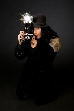 Retro style female photographer with vintage camera and flash