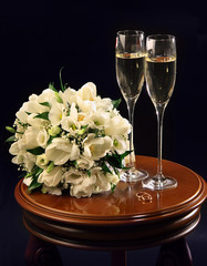 Two wine glasses of champagne and wedding bouquet