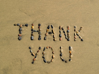Thank you phrase written on beach sand