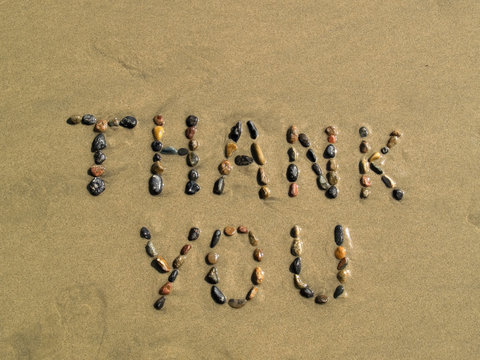 Thank you phrase written on beach sand