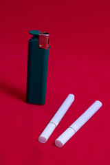 two cigarettes and   lighter on red background