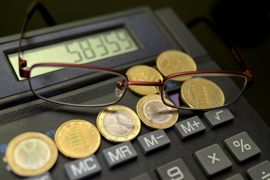 Kalkulator mit Münzen und Brille