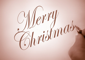 person writing merry christmas in calligraphy in sepia