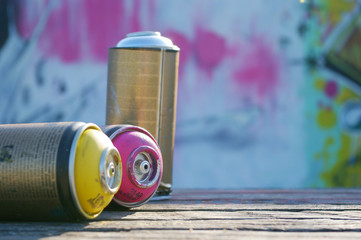 empty, used aerosols with graffiti sprayed wall