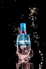 Perfume bottle with water splashes, isolated on black background
