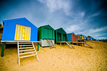 Colourful beach huts with dramatic sky