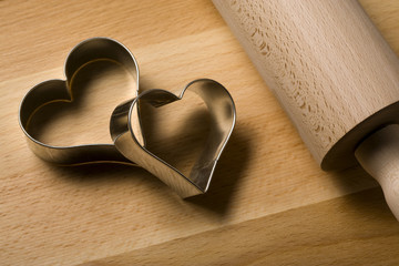 two heart shaped cookie cutters on wooden board