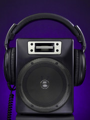 A speaker and a headphone set over a purple background.