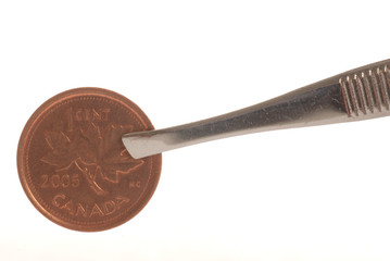canadian penny being pinched with pair of tweezers