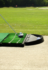 a golf club and ball at the driving range