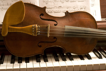 Old violin lying on piano keys